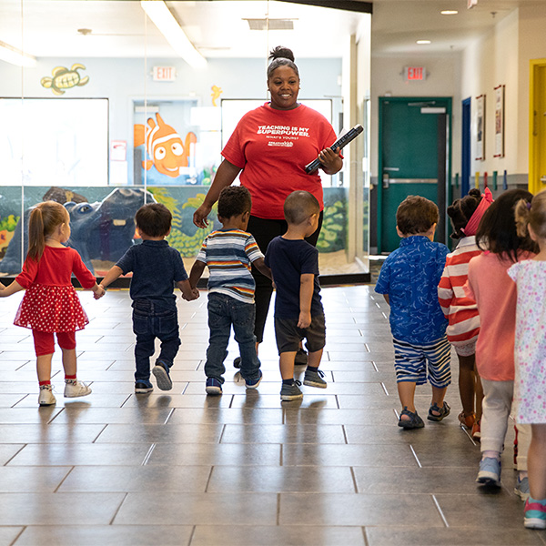 Teacher walking with kids at creative kids learning center hallway