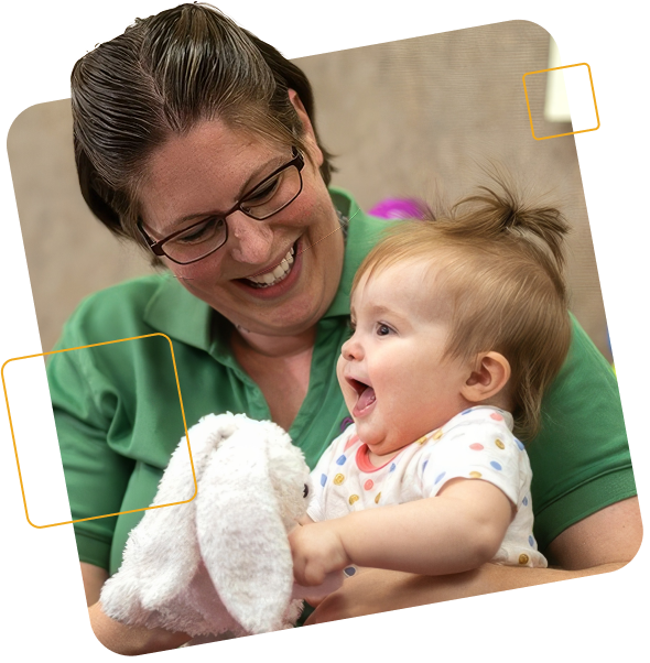 Teacher with baby on her lap holding stuffed bunny