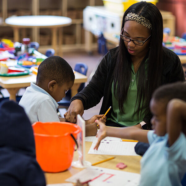 A teacher working with a group of students at a table in the classroom