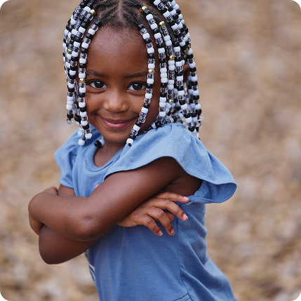 Little girl smiling outside with her arms crossed