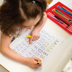 girl tracing letters in preschool