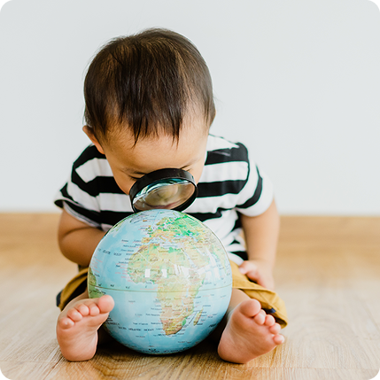 Young boy with magnifying glass looking at globe