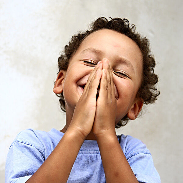 Little boy smiling with hands in prayer