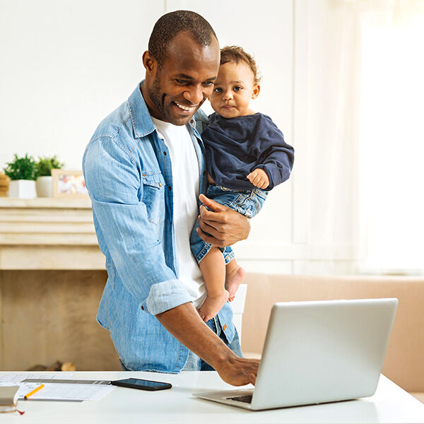 Dad holding child while working on laptop